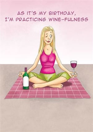 A woman is sitting on a yoga mat with a bottle of wine and a glass of wine.