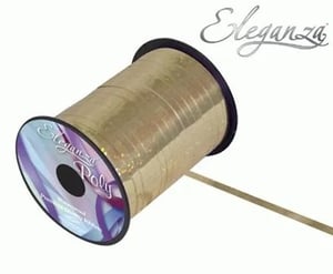 A spool of gold ribbon is sitting on a white surface.