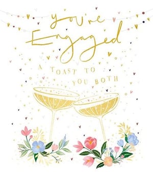 a greeting card that says `` you 're engaged a toast to you both '' with two champagne glasses and flowers .