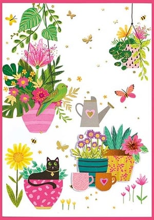 a cat is sitting in a potted plant with flowers and a watering can .