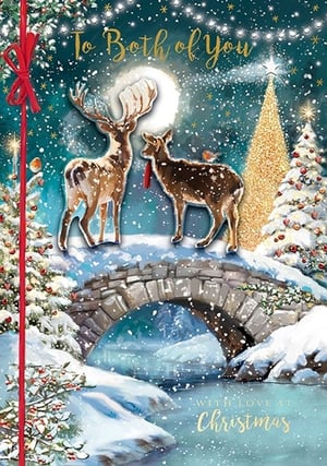 two deer are standing on a bridge in the snow with a christmas tree in the background .