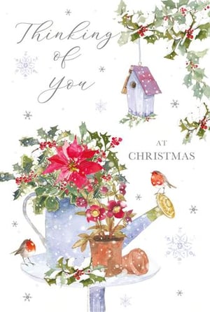 a christmas card with a watering can filled with poinsettia flowers and holly .