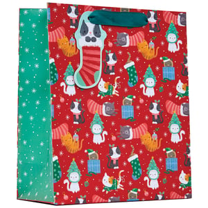 a red gift bag with cats and christmas trees on it