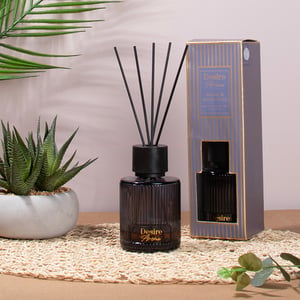 a desire home reed diffuser sits on a table next to a plant