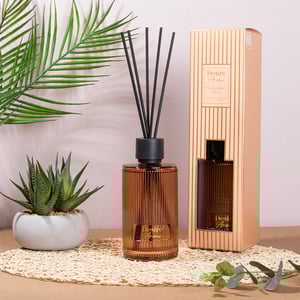 a desire home reed diffuser sits on a table next to a plant