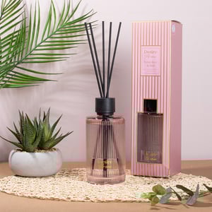 a desire aroma reed diffuser sits on a table next to a plant