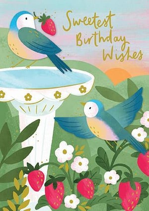 two birds are drinking water from a bird bath surrounded by strawberries and flowers .