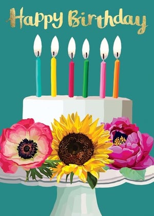a birthday cake with candles and flowers on a cake stand .
