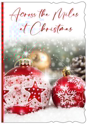 Help your customers send warm wishes this Christmas with our charming "Across The Miles" card. This delightful design features two festive red baubles, one adorned with stars and the other with a delicate snowflake, resting in a bed of sparkling snow. The elegant script "Across the Miles at Christmas" beautifully conveys a heartfelt message to loved ones who may be far away during the festive season. With its enchanting imagery and decorative border, this card offers a truly special way to connect. Supplied by Out of The Blue Studios Ltd., each pack contains 6 cards, ready for your retail display.