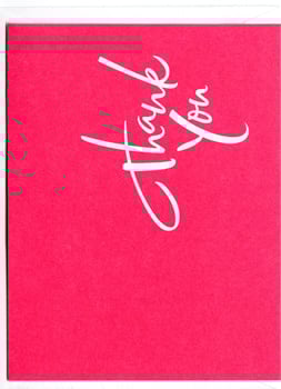 A pink thank you card with white writing on it.