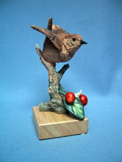 A statue of a bird sits on a tree branch.